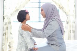 mother making kid wear abaya